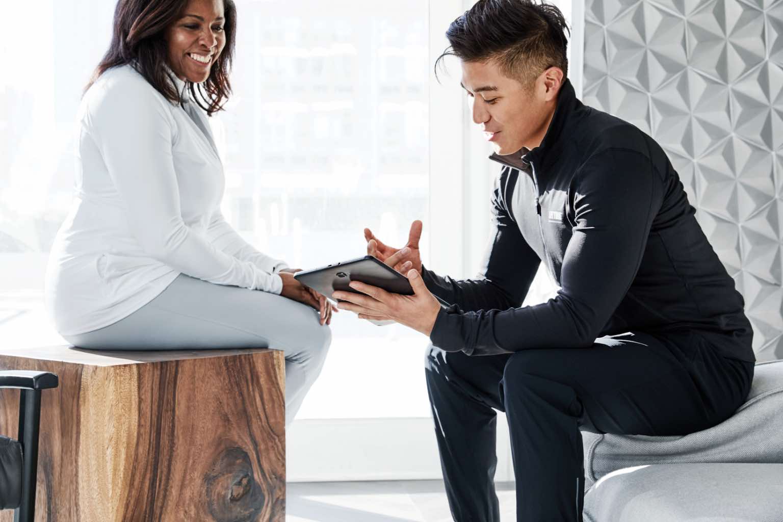 Male personal trainer consulting with a female member during her onboarding session at Life Time. 