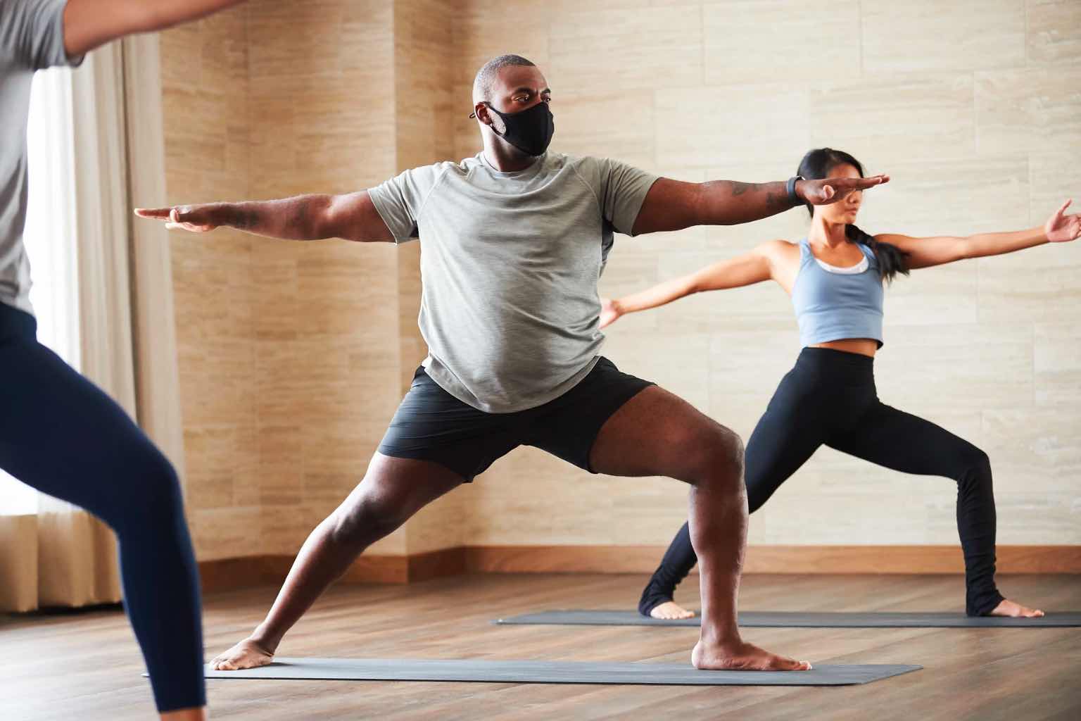 a group of people wearing masks in a yoga class