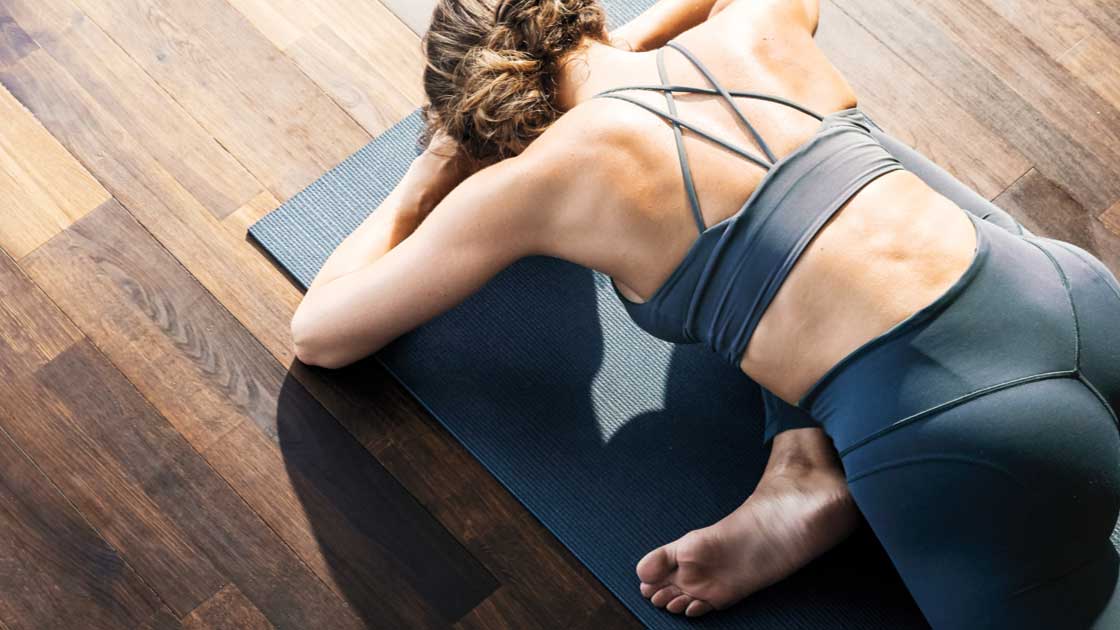 A woman on a yoga mat in a stretching pose