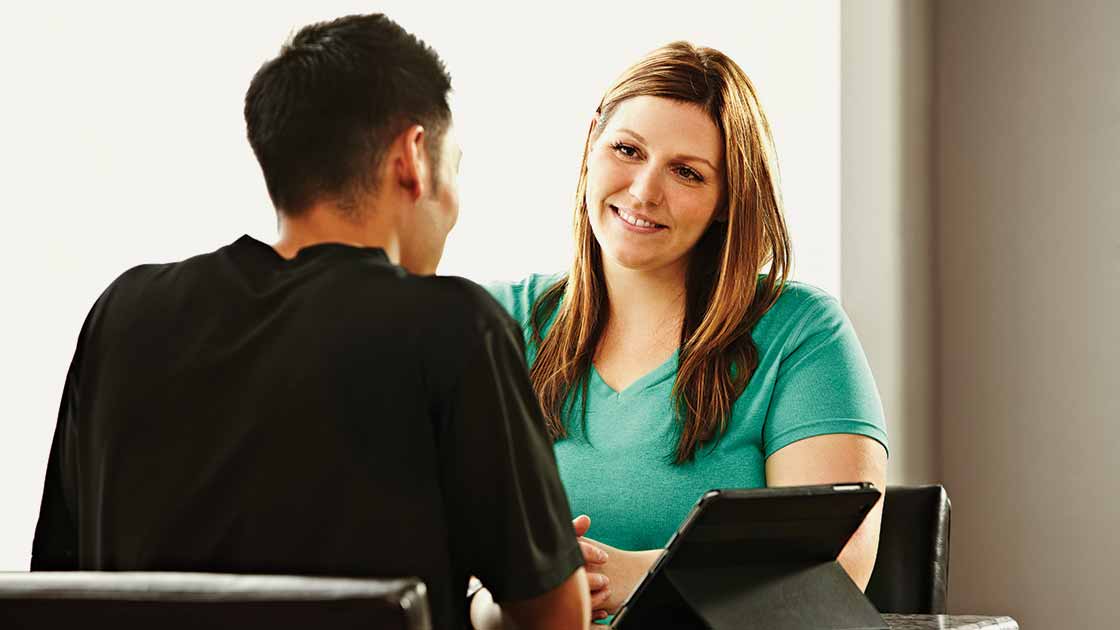 A woman sitting at a desk and talking with a nutritionist