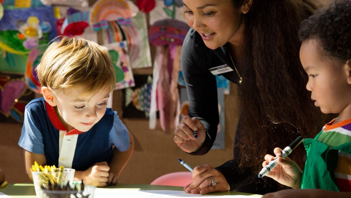 A woman teaching a child to draw