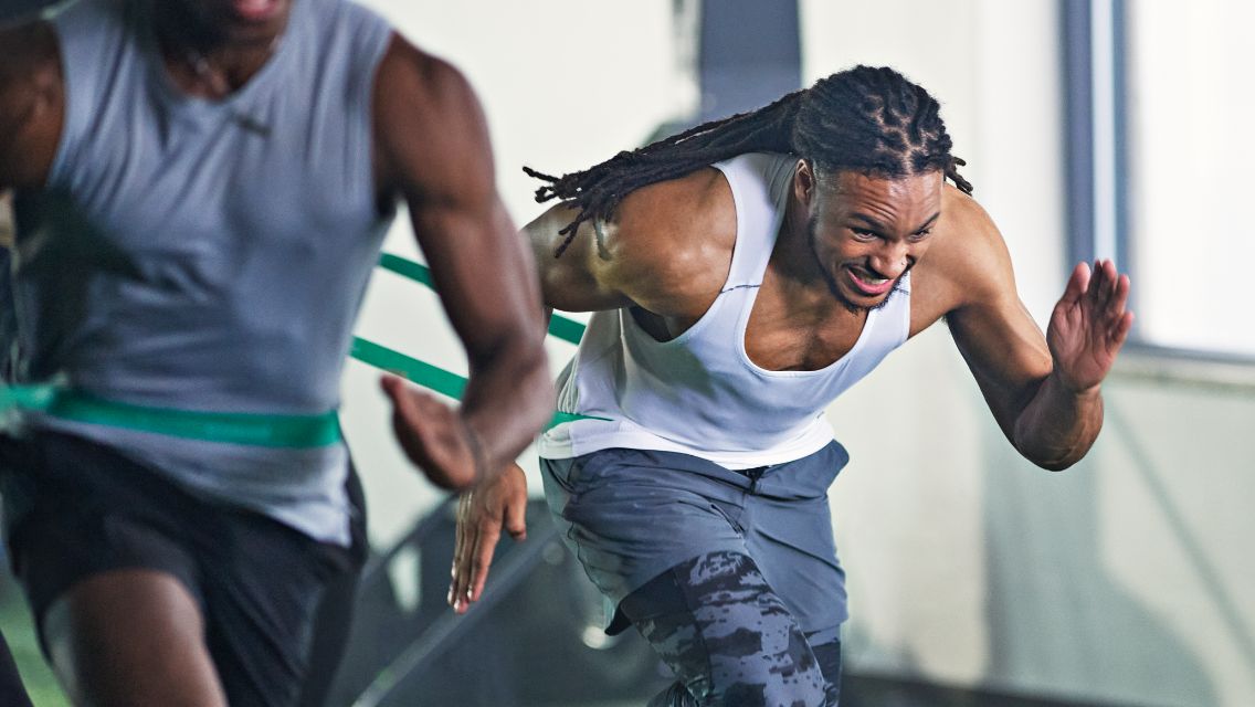 2 men running gameface resistance drill with green resistance bands around their waiste