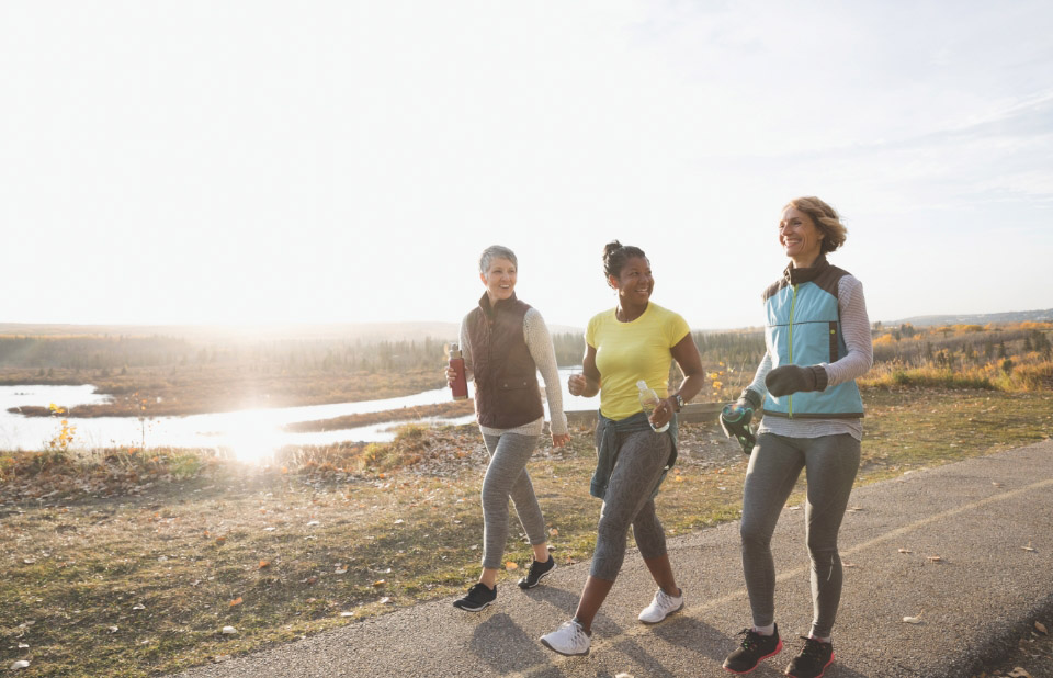 3 women walk and talk along a path outside