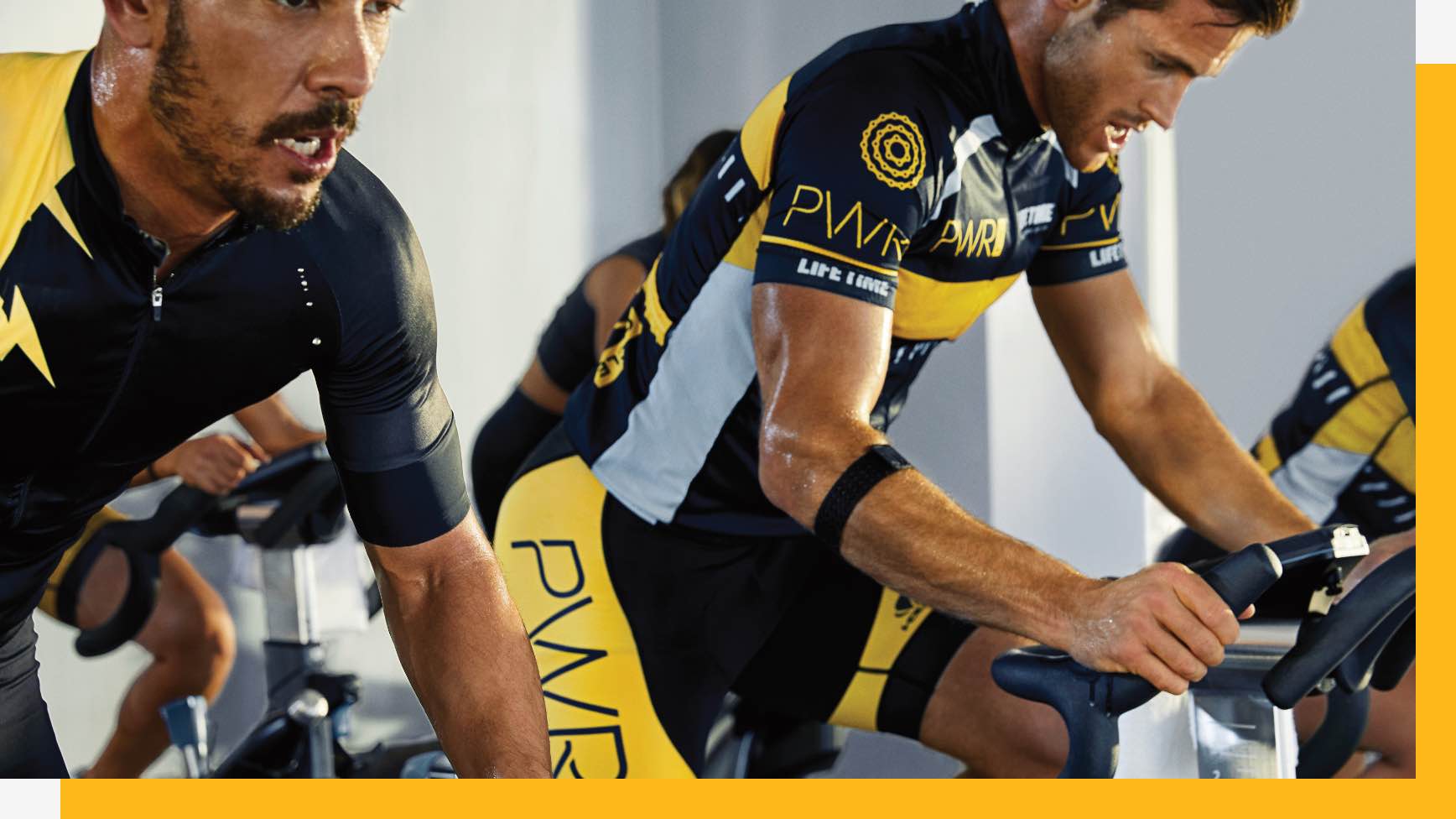 Two men riding bikes in class together