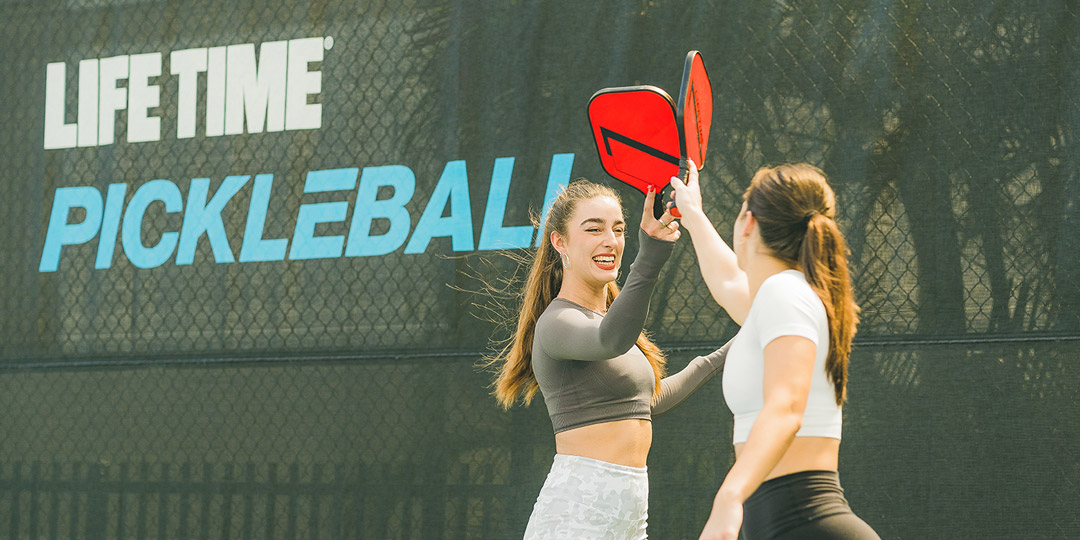 two woman high fiving paddles