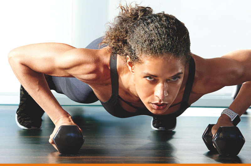 A woman in plank position with dumbbells
