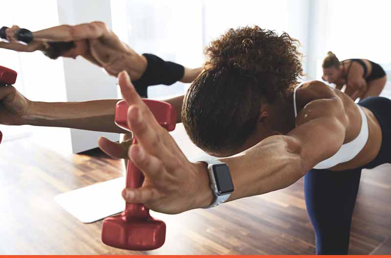 Woman standing on one leg bent over while holding dumbbells
