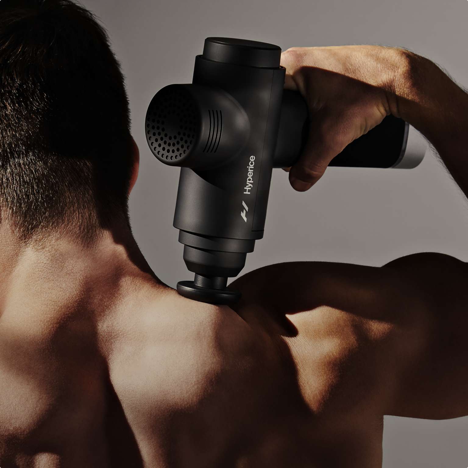 a man using a massage gun on his shoulders